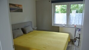 A bedroom with a bed, a window with a curtain, a radiator, and a painting on the wall. - Holidays, holidays and sea (Wilhelmshaven)