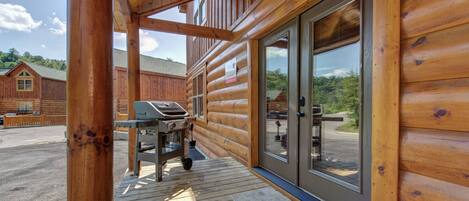 A wooden cabin with a covered porch, a grill, and a sliding glass door.