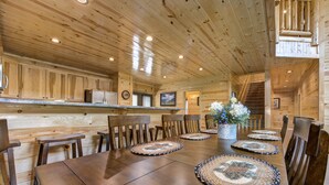 Ein Holzinterieur mit einem Esstisch, der für sechs Personen gedeckt ist, umgeben von Stühlen.