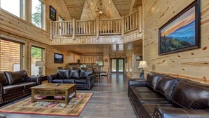 Ein geräumiger Innenraum einer Hütte mit hoher Decke, Holzwänden und einem Balkon.