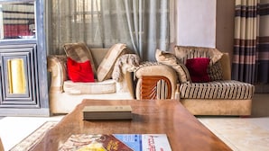 A living room with a wooden coffee table, a sofa with striped cushions, and a red pillow.