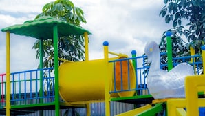 A playground with a yellow slide, a green climbing structure, and a blue fence.