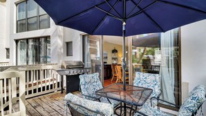 An outdoor patio with a grill, seating, and a large umbrella. - Reduced Rates! Short Walk to the Beach and Pool! (Hilton Head Island)