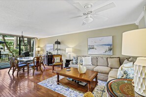 A spacious living room with a ceiling fan, a dining area with chairs and a table, a sofa, and a coffee table.