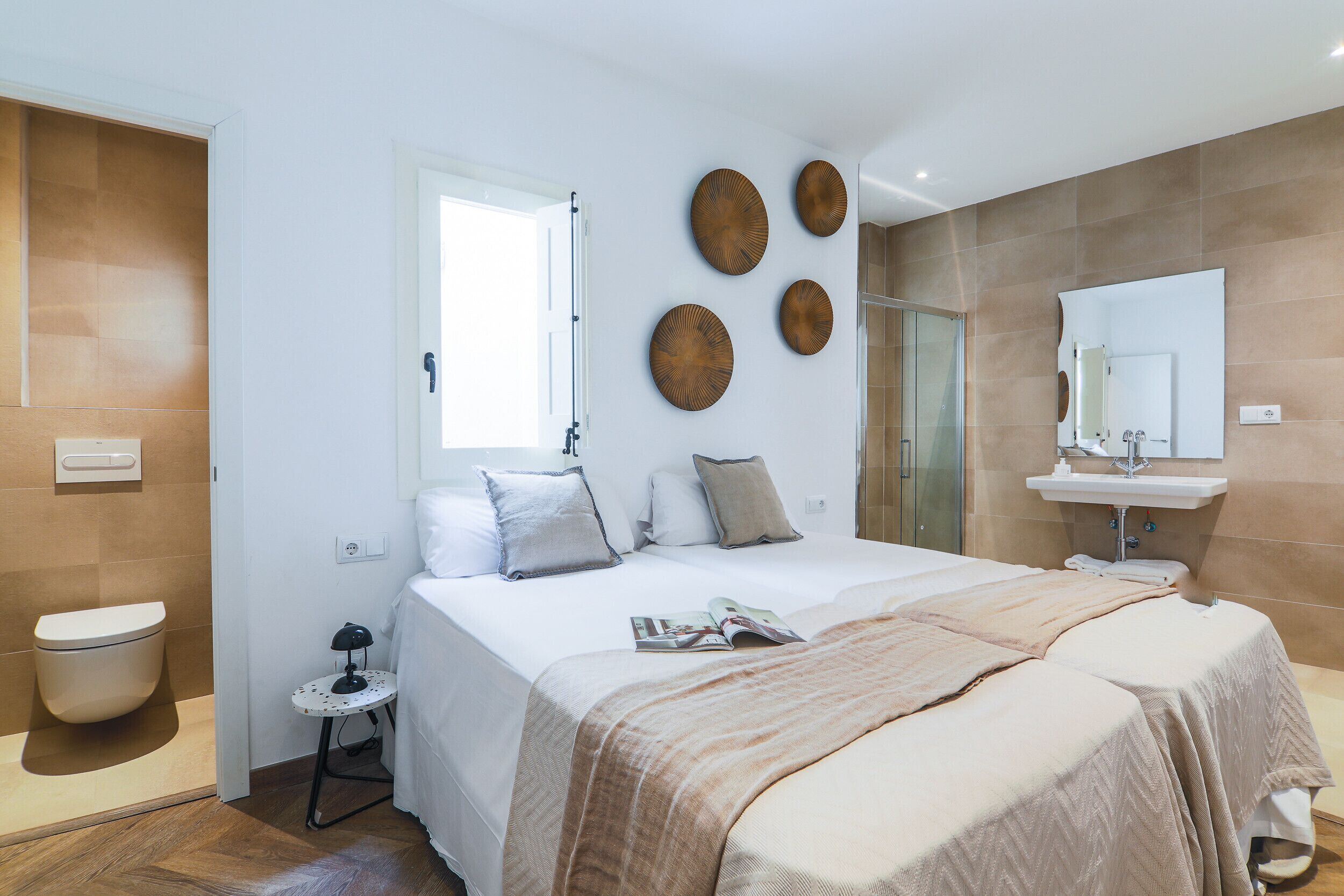 A hotel room with a bed, bedside table, and a bathroom with a sink and mirror.