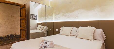 A hotel room with a large bed, a wooden wardrobe, and a mirror on the wall.