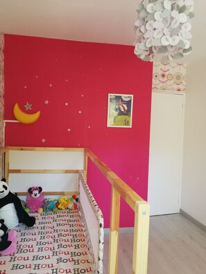 A child's bedroom with a pink wall, a wooden bunk bed, and a ceiling fan.