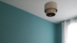 Ein Schlafzimmer mit türkisfarbenen Wänden, einem weißen Bett und einem Nachttisch mit Lampe.
