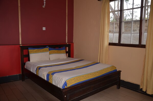 Una cama con estructura de madera y colcha blanca y azul.