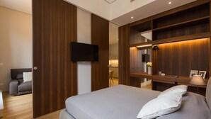 A modern bedroom with a large bed, a TV mounted on the wall, and a wooden wardrobe. - Amazing Piazza Venezia Suite Int 20 (Roma)