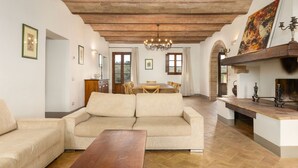 Un salon spacieux avec un plafond en bois, un canapé, une table à manger et une cheminée.