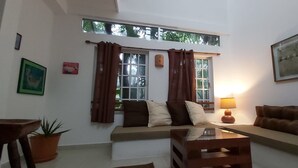 Ein Wohnzimmer mit einer Couch, einem Couchtisch, einer Lampe und einem Fenster mit Vorhängen.