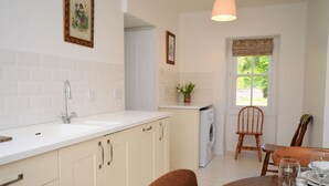 A kitchen with a sink, cabinets, and a dining area with a table and chairs. - Garden cottage, estate property set in amazing gardens, pet friendly, Wi-Fi (Strachur)