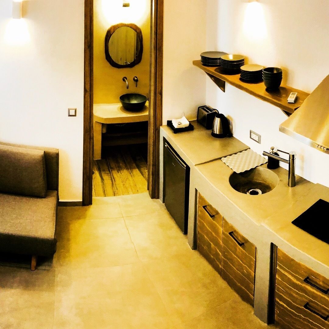 Una habitación de hotel compacta con kitchenette, un baño pequeño y un sofá.