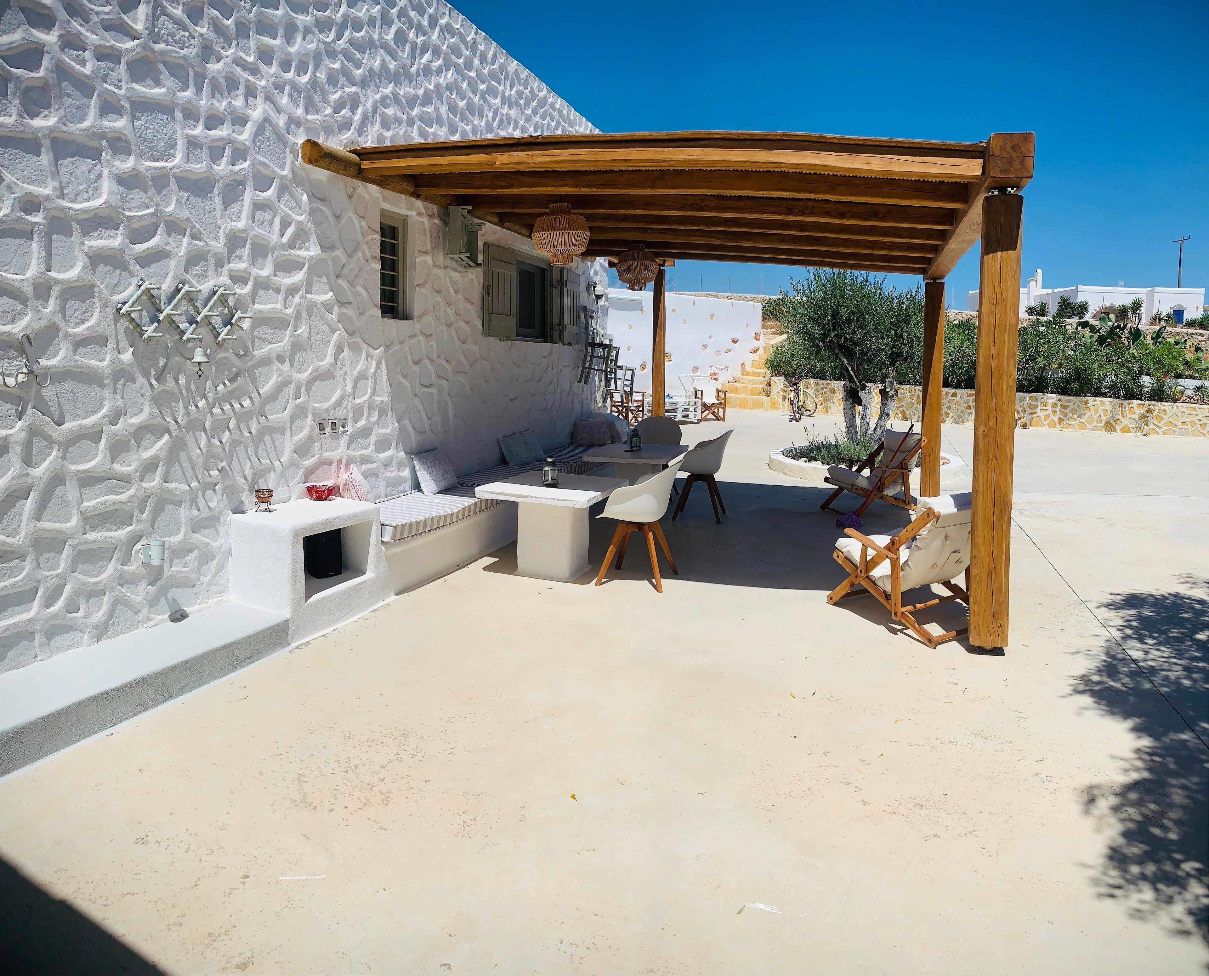Un espacio de estar al aire libre con techo, una pared de piedra, una pérgola de madera y mobiliario exterior.