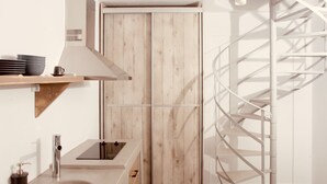 A modern kitchen with a wooden cabinet, a stainless steel sink, and a spiral staircase. - Aeris suites (Naxos)