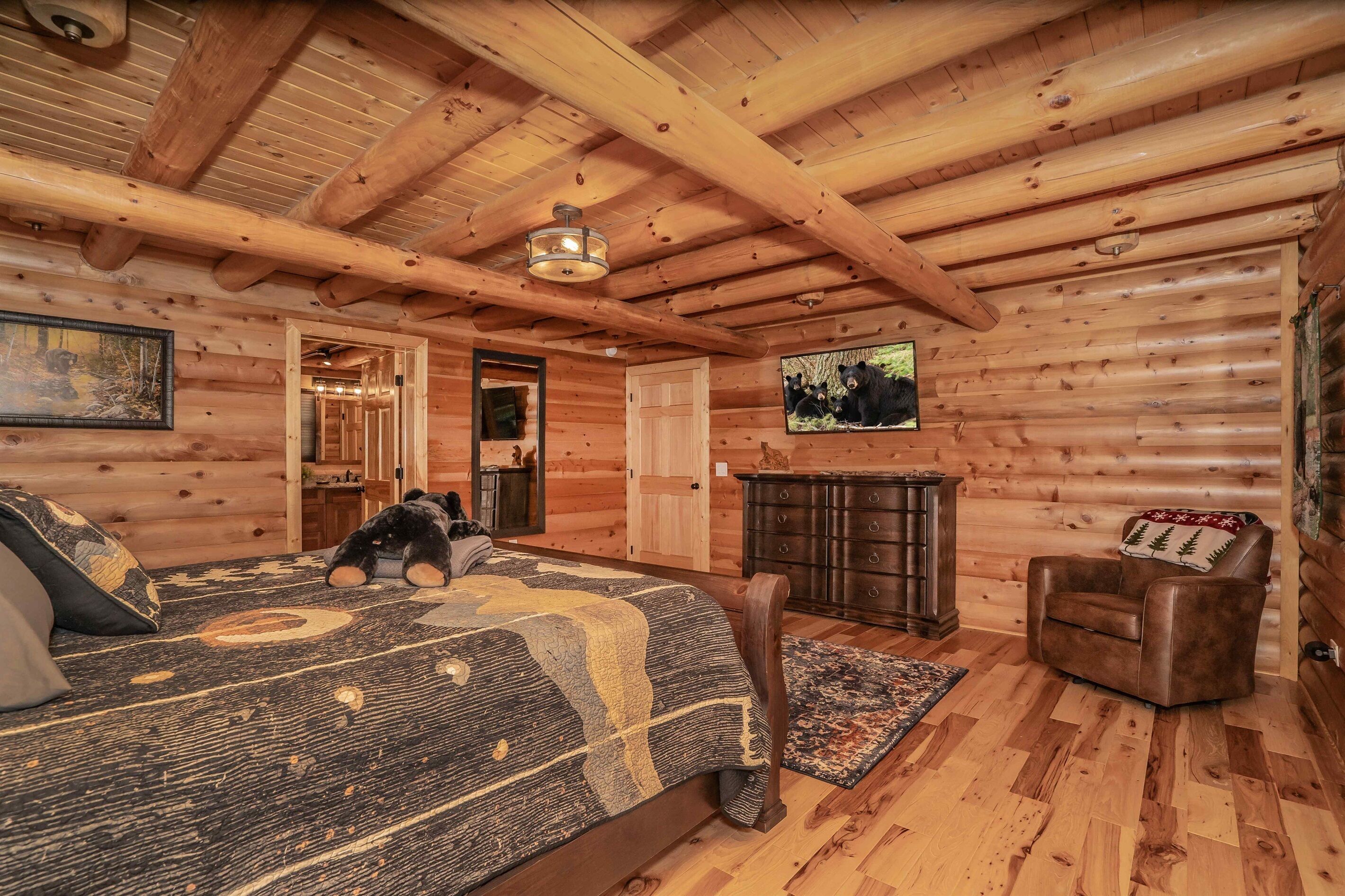 Un dormitorio tipo cabaña de madera con cama, cómoda y televisor en la pared.