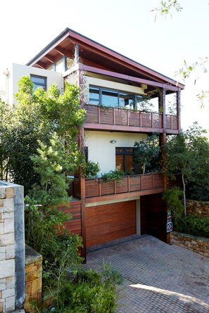 A two-story modern house with a wooden balcony, a garage, and a brick driveway. - Table Mountain Villa (Cape Town)