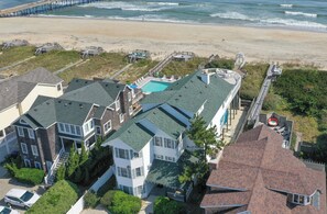 A coastal residential area with houses, a beach, and a pier.