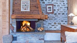 A stone fireplace with a wooden mantel, a framed sign above it, and a stone wall in the background.
