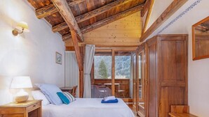 A bedroom with two beds, wooden furniture, a view of the outdoors, and a large wooden wardrobe.