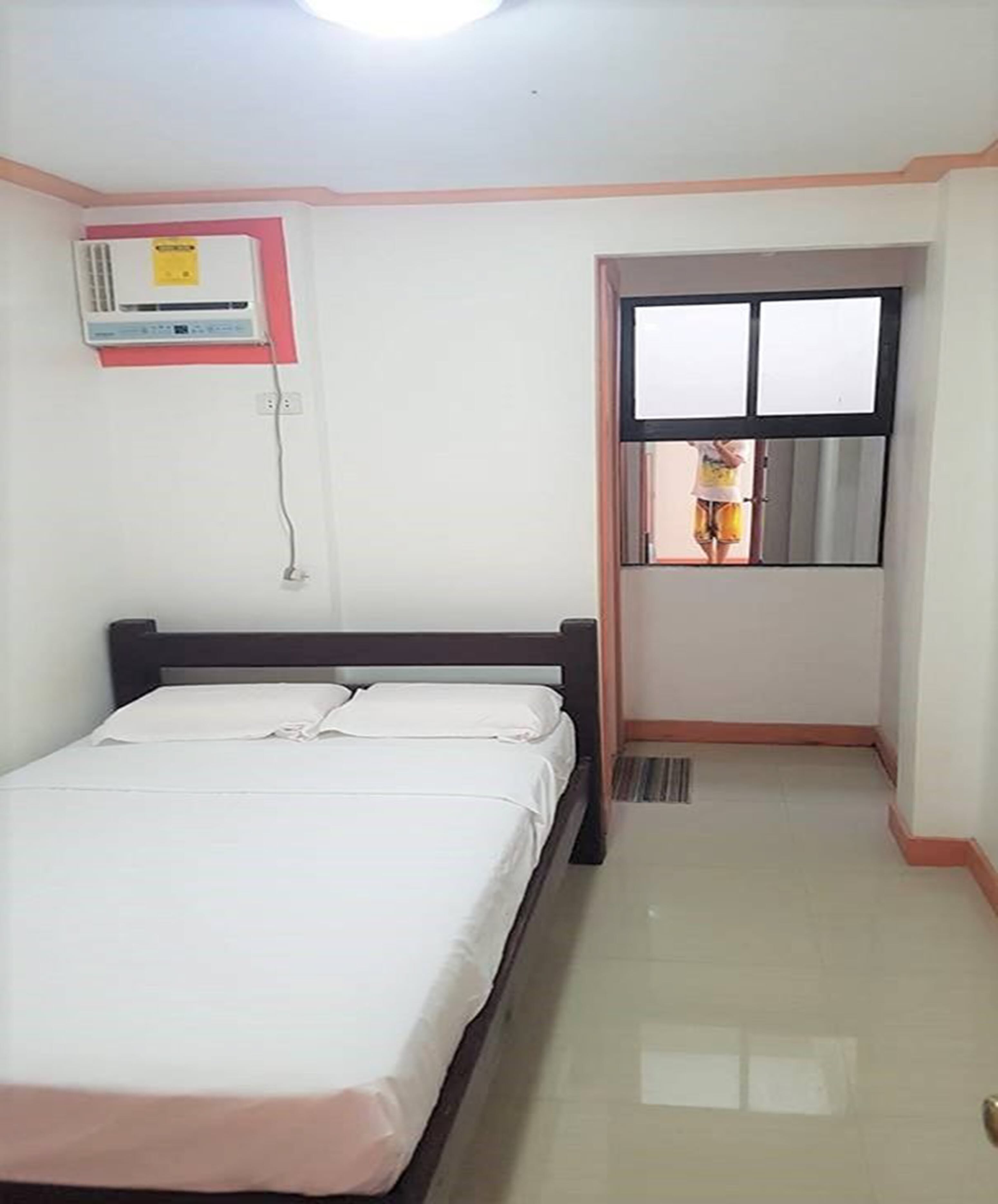 Un dormitorio con cama, aire acondicionado, ventana y puerta.