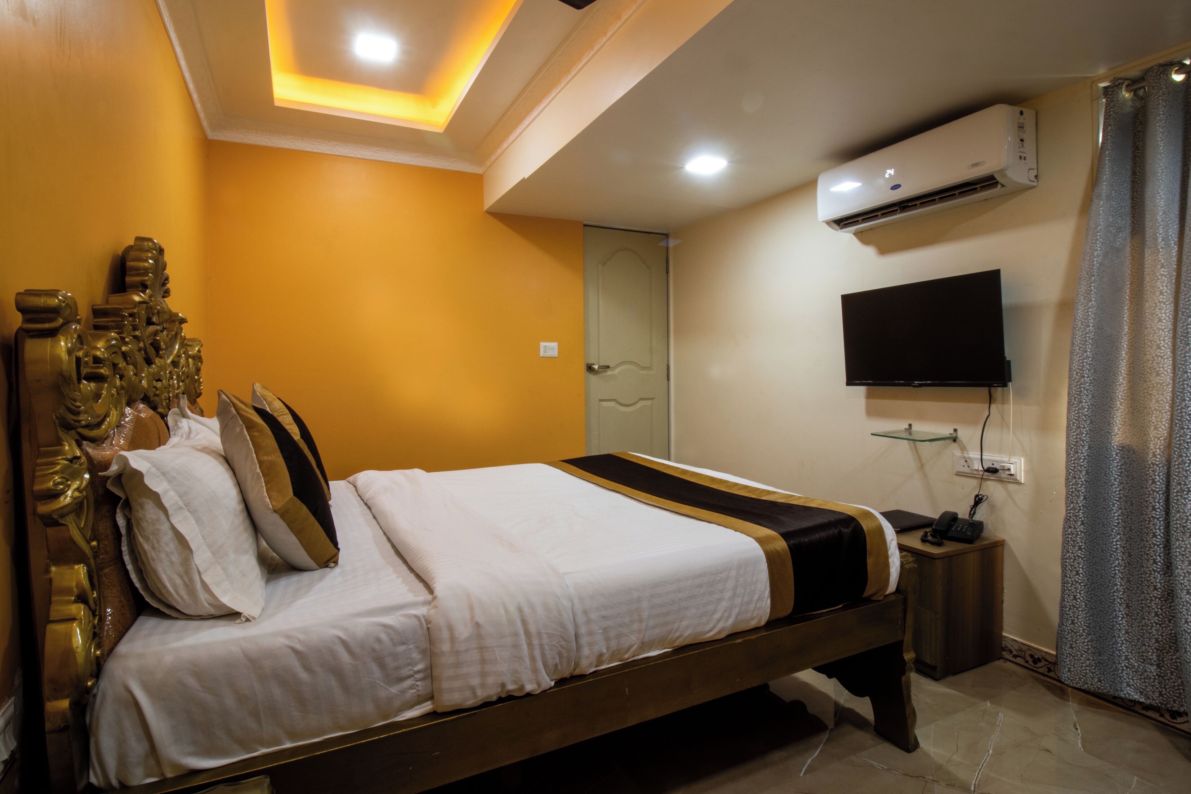 A hotel room with a bed, a television, an air conditioner, and a nightstand.