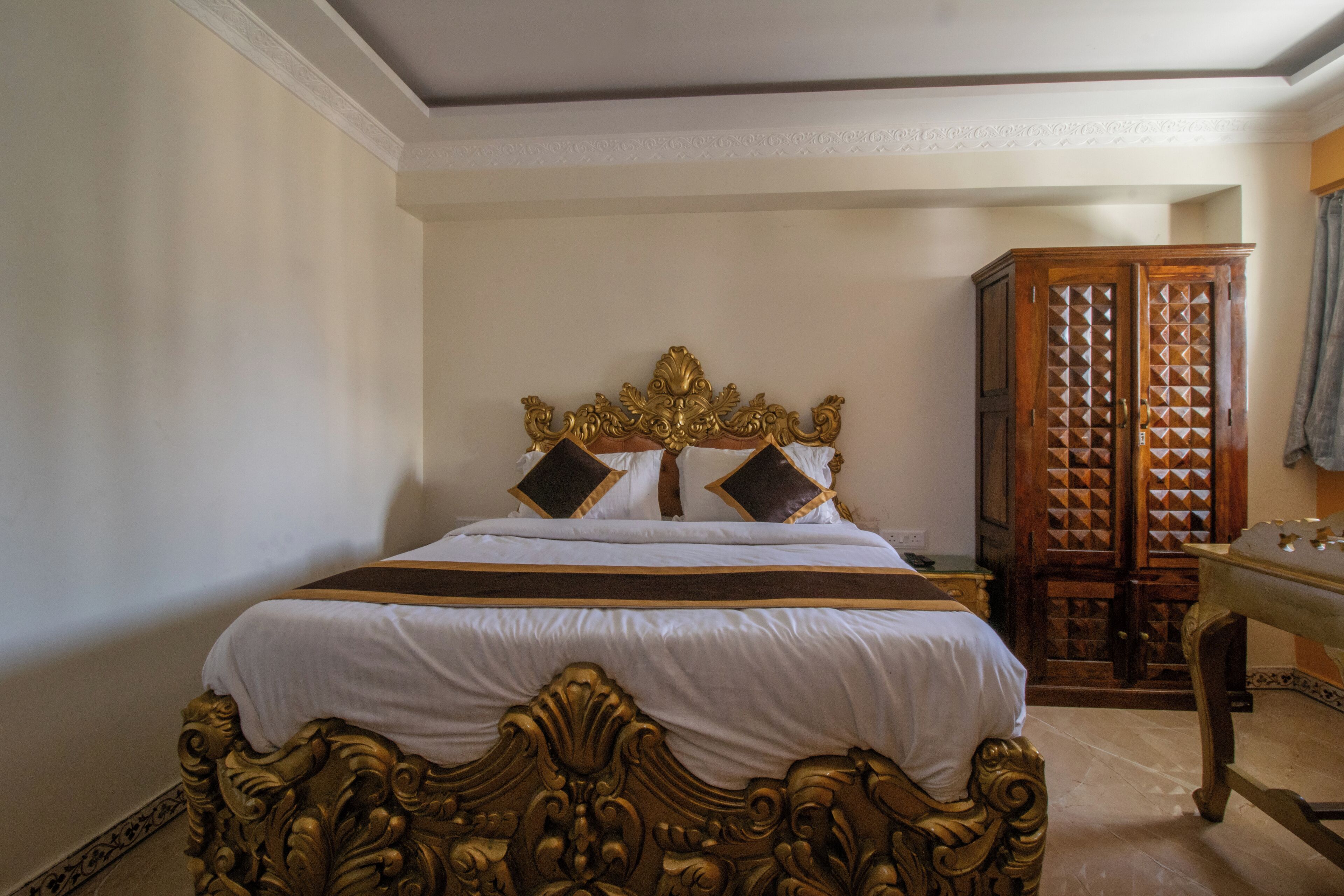 Un dormitorio con una cama grande, cabecera decorada y un armario de madera.