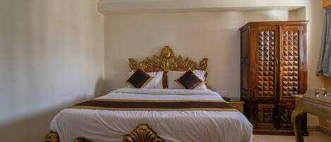 A bedroom with a large bed, ornate headboard, and a wooden wardrobe.
