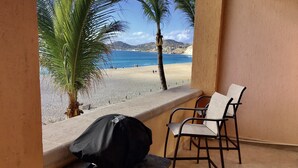 Un balcon donnant sur une plage, une chaise et une table sur laquelle se trouve un sac.