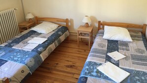 A twin room with two wooden beds, each with a nightstand and a table lamp. - Gîte "le Grand Ferrand" (Saint Etienne en Dévoluy)