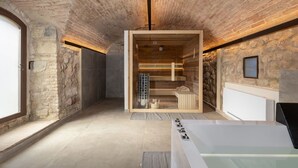 A spa room with a stone wall, a wooden sauna, and a white bathtub. - Villa Simone - Luxury Villa with swimming pool (San Gimignano)