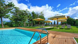 A swimming pool with clear blue water, surrounded by wooden deck and lounge chairs. - Villa Simone - Luxury Villa with swimming pool (San Gimignano)