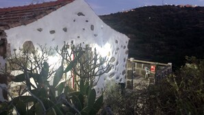 Un edificio con fachada blanca y tejado de tejas rojas, rodeado de cactus y arbustos.