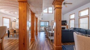 A spacious living area with wooden pillars, a blue sofa, and a television.