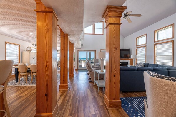A spacious living area with wooden pillars, a blue sofa, and a television.