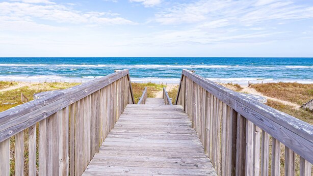 A wooden boardwalk leading to the beach with a clear view of the ocean.
