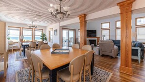 A spacious living area with a large wooden dining table, comfortable seating, and a fireplace.