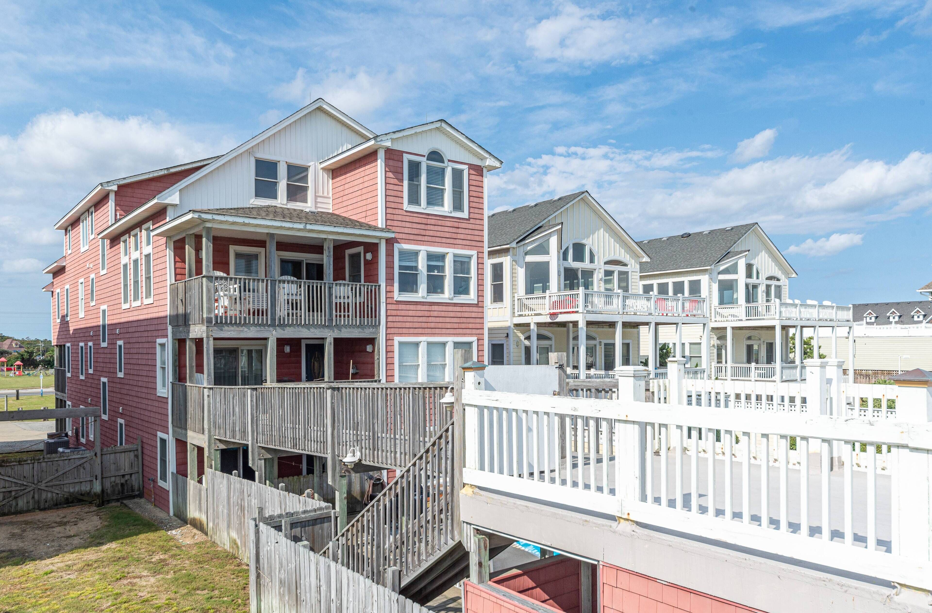 A multi-story residential building with balconies, a wooden fence, and a clear sky.