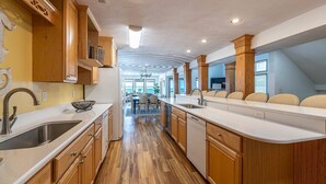 A modern kitchen with wooden cabinets, a central island, and a view to the dining area.