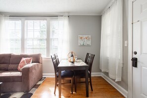 Un coin repas avec une table dressée pour quatre personnes, un canapé et une porte dotée d’une serrure.