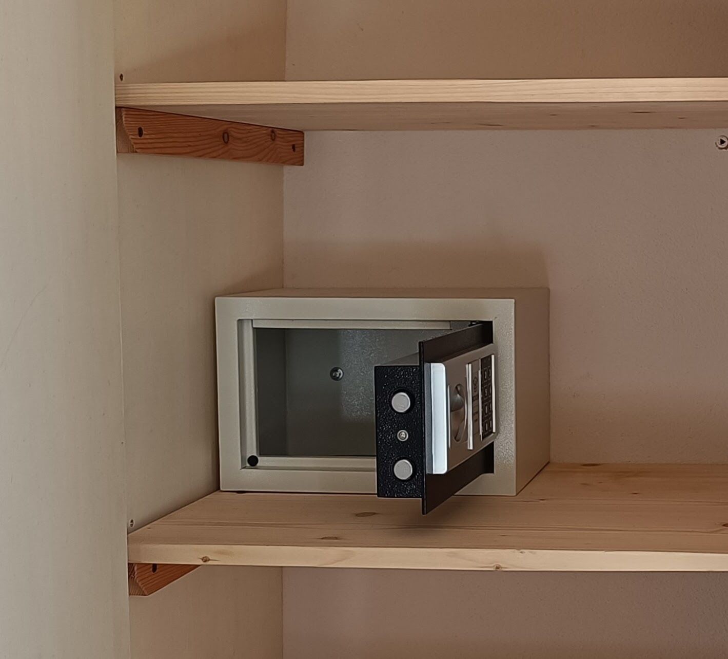 A corner of a room with a white-framed object, possibly a television, on a shelf.