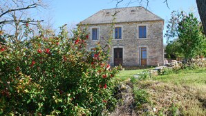 Un bâtiment en pierre doté d’un toit à pignon, d’une entrée centrale et d’un petit porche.