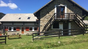 Ein Steinhaus mit einer Holztreppe und einem Picknicktisch davor.