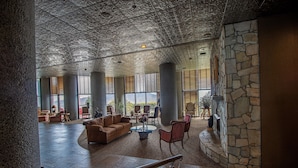 A spacious lobby with a high ceiling, stone columns, and a stone fireplace. There are several seating areas with couches and chairs. - Top Floor 2B Condo w/ Pool Access! (Sugar Mountain)