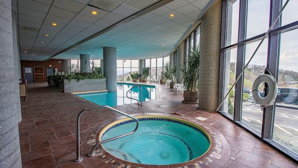 An indoor swimming pool with a tiled floor, a metal ladder, and large windows offering a view of the outside. - Top Floor 2B Condo w/ Pool Access! (Sugar Mountain)