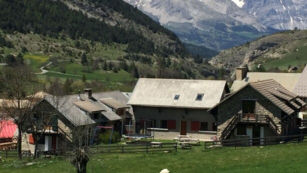 A mountain village with traditional stone buildings, a playground, and a view of snow-capped peaks. - Gîte "le Beau Rêve": Group of 27 people max (Saint Etienne en Dévoluy)