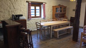 A rustic kitchen with a wooden table, bar stools, and a stone wall. - Gîte "le Beau Rêve": Group of 27 people max (Saint Etienne en Dévoluy)