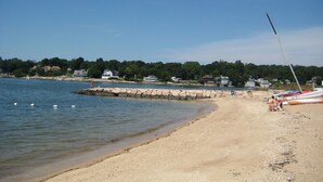 Une plage avec des bateaux, une jetée et des maisons en arrière-plan.