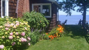 Une maison avec une cheminée en briques, une véranda avec un fauteuil et une vue sur la mer.